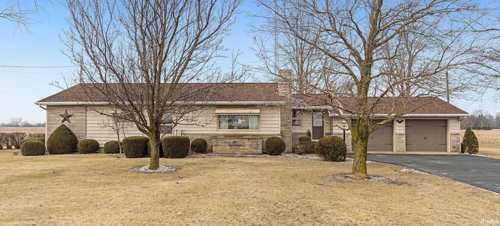 ranch-style house featuring a front lawn, aphalt driveway, a chimney, a garage, and stone siding