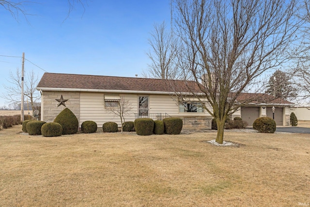 view of home's exterior with a lawn, driveway, stone siding, a shingled roof, and a garage