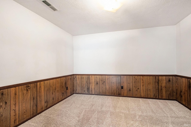 empty room with a wainscoted wall, wood walls, and visible vents