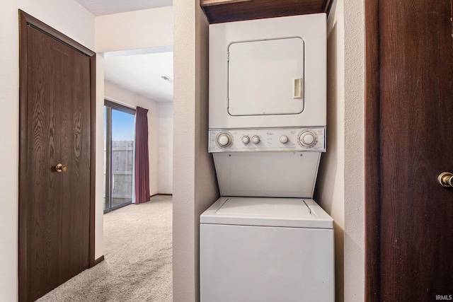 laundry area with a textured wall, stacked washer / drying machine, and carpet floors