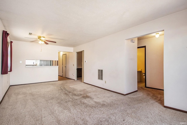 unfurnished living room featuring baseboards, visible vents, carpet floors, ceiling fan, and a textured ceiling