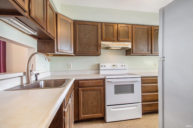 kitchen with under cabinet range hood, white appliances, light countertops, and a sink