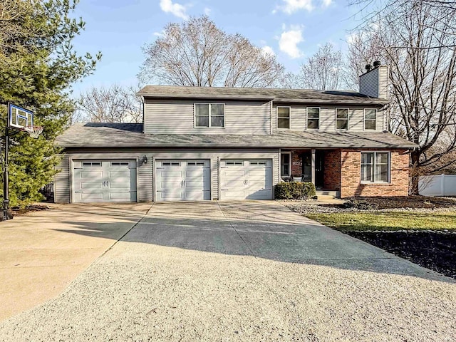 traditional-style house with brick siding, an attached garage, a chimney, and driveway