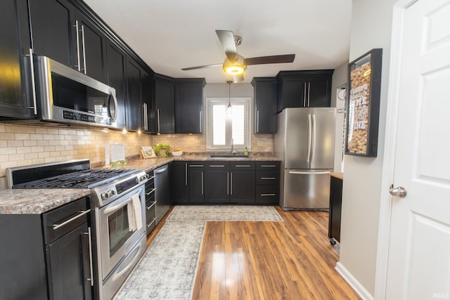 kitchen featuring ceiling fan, a sink, appliances with stainless steel finishes, dark cabinets, and backsplash