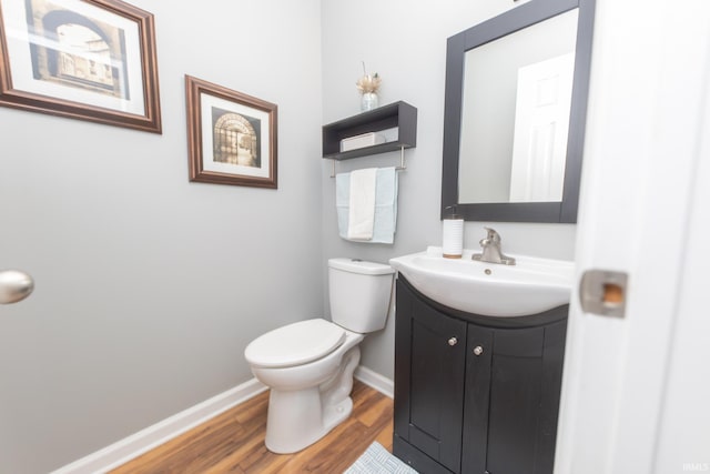 bathroom featuring toilet, vanity, baseboards, and wood finished floors