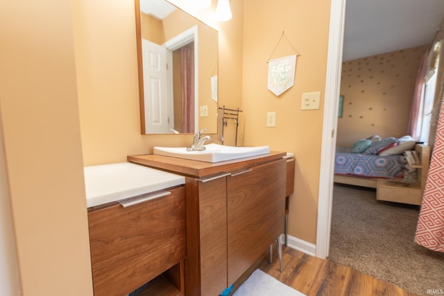 bathroom featuring vanity, ensuite bath, wood finished floors, and baseboards