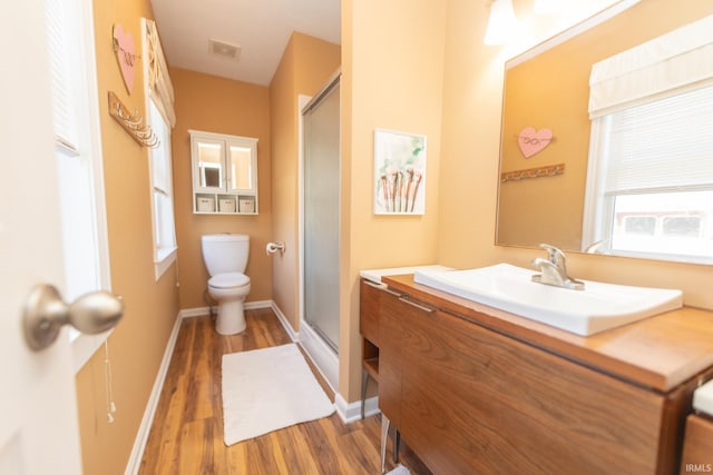 bathroom featuring vanity, wood finished floors, baseboards, a shower stall, and toilet