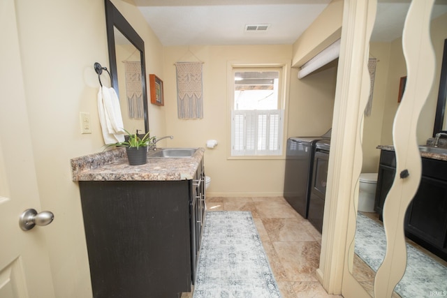 bathroom featuring vanity, toilet, separate washer and dryer, and visible vents