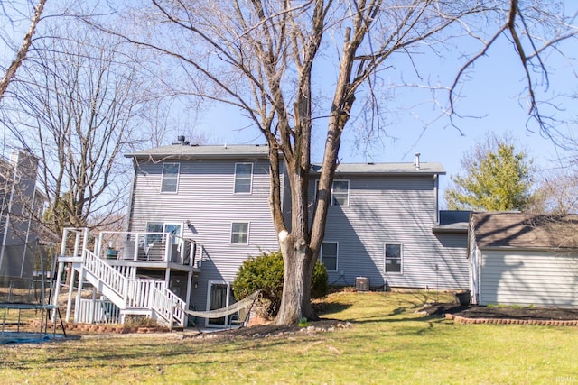 back of house featuring a deck, a trampoline, central AC, stairway, and a yard