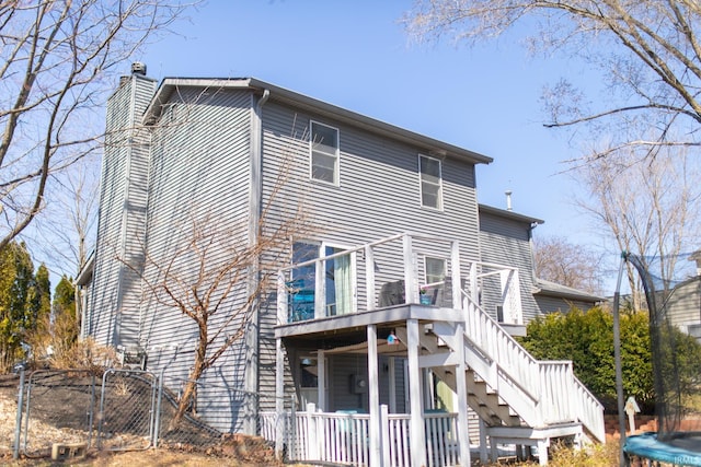 rear view of house with a gate, fence, a wooden deck, a chimney, and stairs