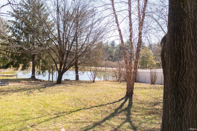 view of yard featuring a water view, a trampoline, and a fenced backyard