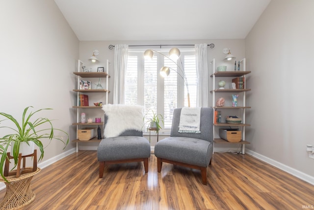 living area with baseboards, lofted ceiling, and wood finished floors