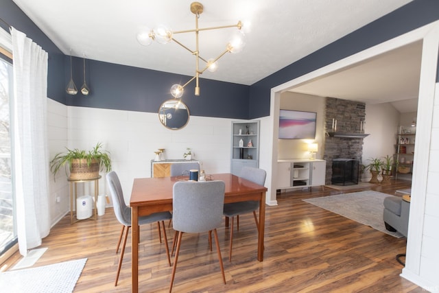 dining area with a fireplace, a notable chandelier, and wood finished floors