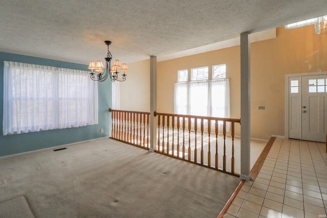 carpeted foyer entrance featuring an inviting chandelier, tile patterned floors, and a textured ceiling