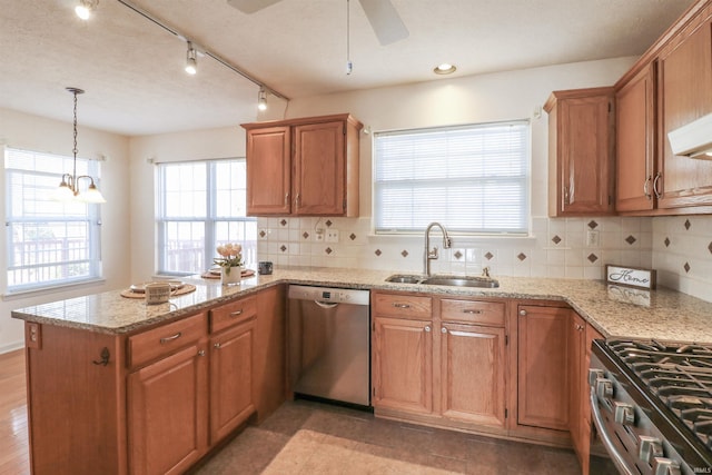 kitchen with light stone counters, a peninsula, stainless steel appliances, and a sink