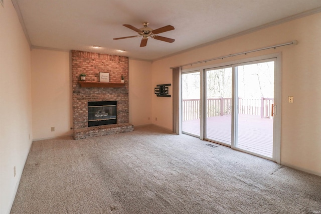 unfurnished living room with a fireplace, ceiling fan, carpet flooring, and ornamental molding