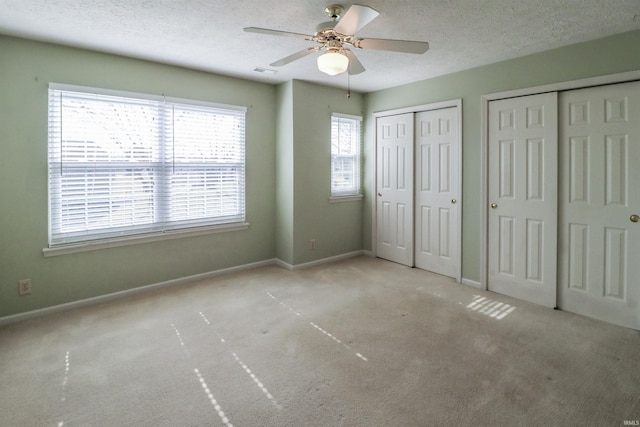 unfurnished bedroom featuring visible vents, baseboards, two closets, and a textured ceiling