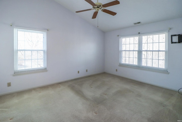 empty room featuring a wealth of natural light, visible vents, carpet floors, and vaulted ceiling