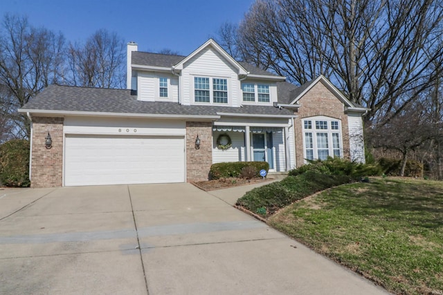 traditional home featuring a front lawn, roof with shingles, concrete driveway, brick siding, and a chimney