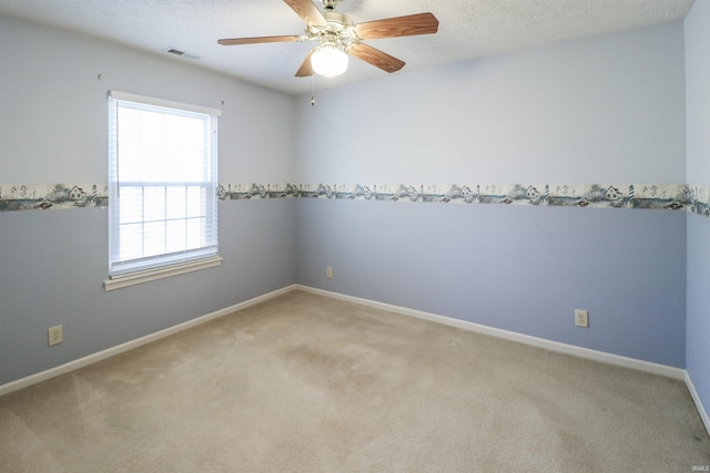 carpeted spare room featuring visible vents, a textured ceiling, baseboards, and ceiling fan