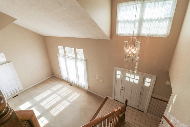 tiled entrance foyer featuring a notable chandelier, a high ceiling, and visible vents