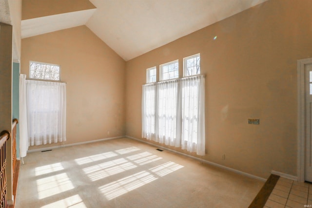 empty room featuring visible vents, baseboards, high vaulted ceiling, and light colored carpet