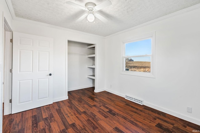 unfurnished bedroom featuring dark wood-style floors, visible vents, a closet, a textured ceiling, and crown molding