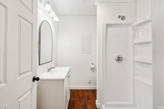 bathroom featuring baseboards, vanity, wood finished floors, a textured ceiling, and a shower