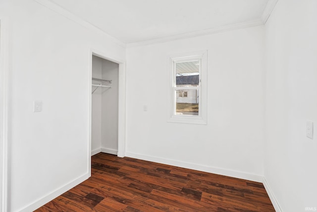 unfurnished bedroom featuring dark wood-type flooring, crown molding, baseboards, and a closet