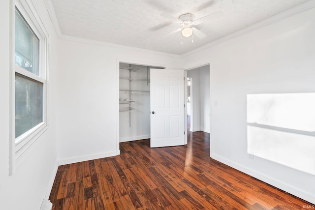 unfurnished bedroom with a ceiling fan, baseboards, ornamental molding, dark wood-type flooring, and a closet