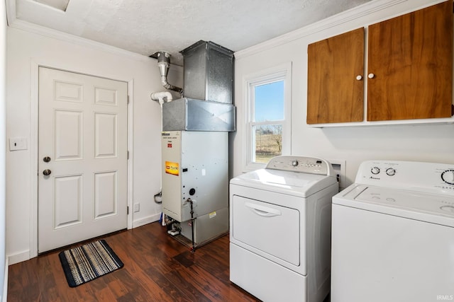 clothes washing area featuring dark wood-style floors, washing machine and dryer, cabinet space, and ornamental molding