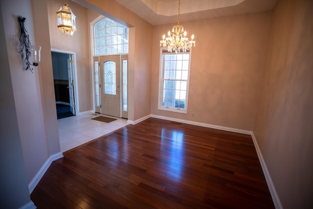 foyer entrance featuring visible vents, a notable chandelier, hardwood / wood-style floors, baseboards, and a towering ceiling