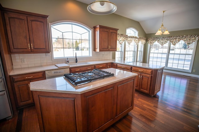 kitchen with stainless steel gas cooktop, light countertops, a peninsula, white dishwasher, and a sink