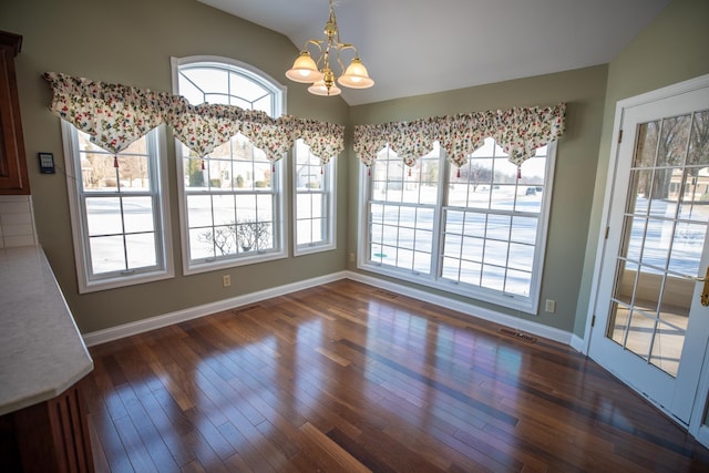 unfurnished dining area featuring wood finished floors, visible vents, lofted ceiling, and a chandelier