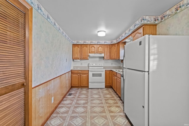 kitchen featuring white appliances, light countertops, under cabinet range hood, and wainscoting