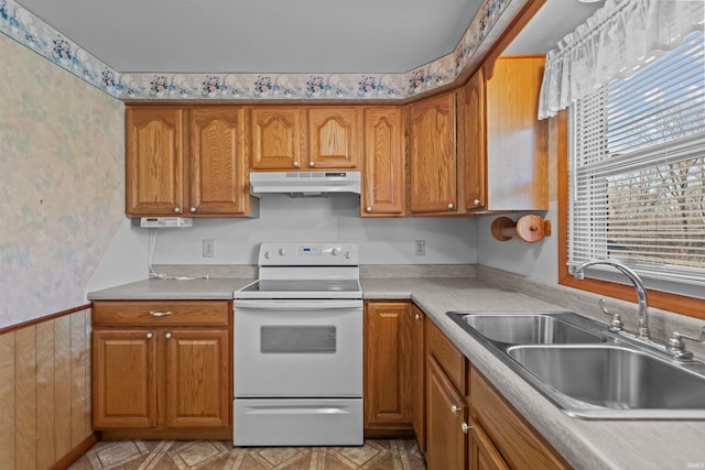 kitchen featuring white range with electric cooktop, brown cabinetry, under cabinet range hood, and a sink