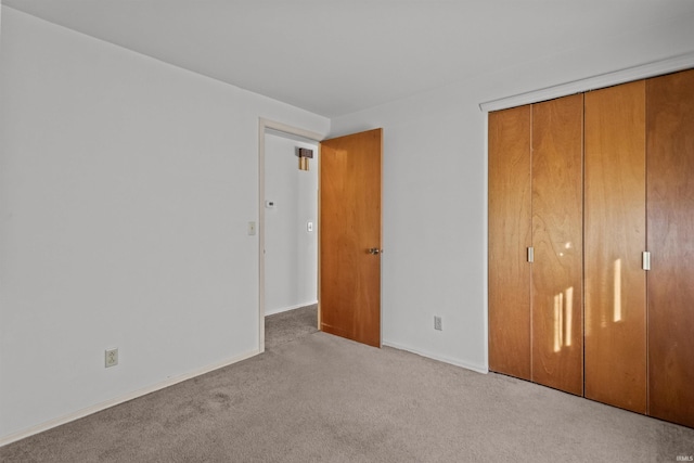 unfurnished bedroom featuring a closet, baseboards, and carpet floors