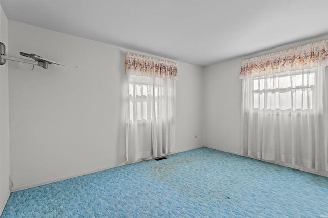 unfurnished room with carpet flooring, plenty of natural light, and visible vents