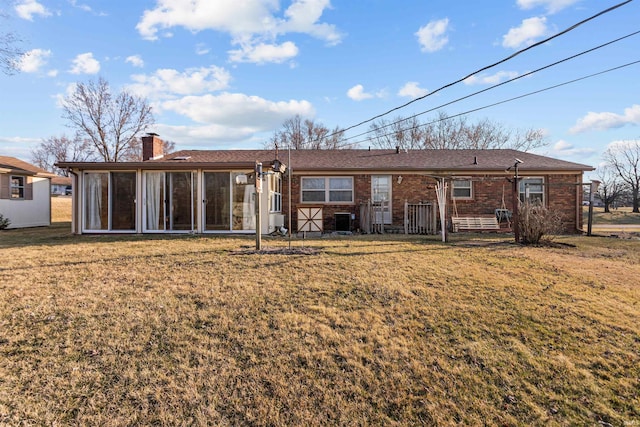 back of house with brick siding, central AC unit, a lawn, a chimney, and a sunroom