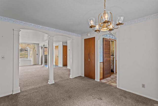 empty room featuring a notable chandelier, baseboards, ornate columns, and carpet floors