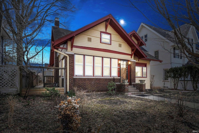 view of front of property featuring brick siding and a chimney