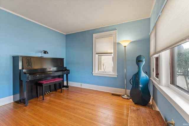 sitting room featuring baseboards, visible vents, wood-type flooring, and ornamental molding