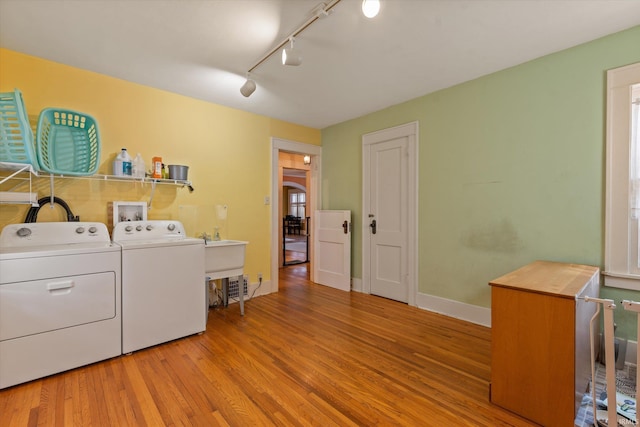 clothes washing area with baseboards, independent washer and dryer, wood finished floors, and laundry area