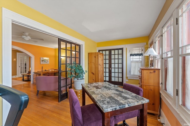 dining room featuring ceiling fan, french doors, arched walkways, and wood finished floors