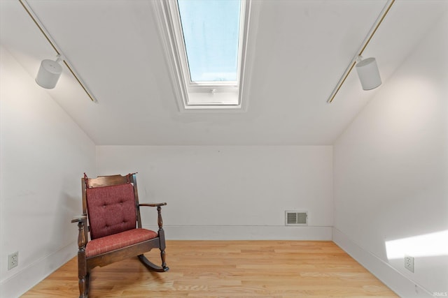 sitting room with visible vents, baseboards, lofted ceiling, and wood finished floors