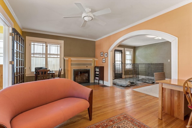 living area with a fireplace with flush hearth, arched walkways, a healthy amount of sunlight, and wood finished floors