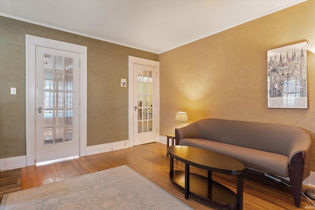 living area featuring crown molding, baseboards, and wood finished floors