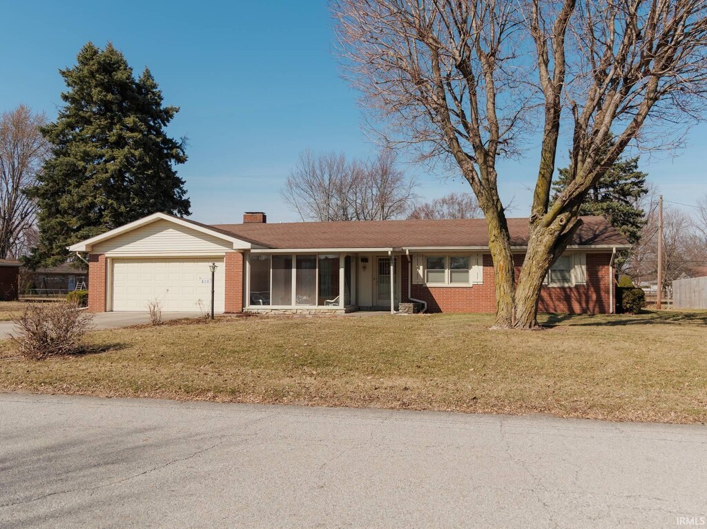 ranch-style home with a front yard, a garage, brick siding, and driveway
