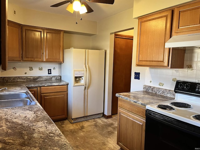 kitchen featuring under cabinet range hood, range with electric stovetop, white refrigerator with ice dispenser, a ceiling fan, and a sink