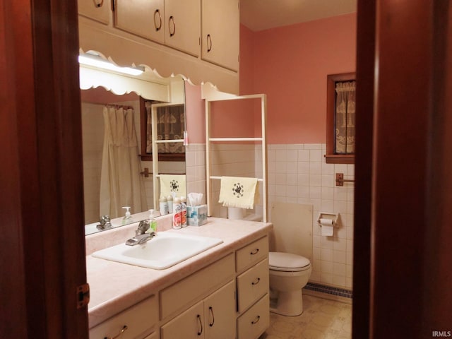 bathroom with a wainscoted wall, toilet, tile walls, and vanity